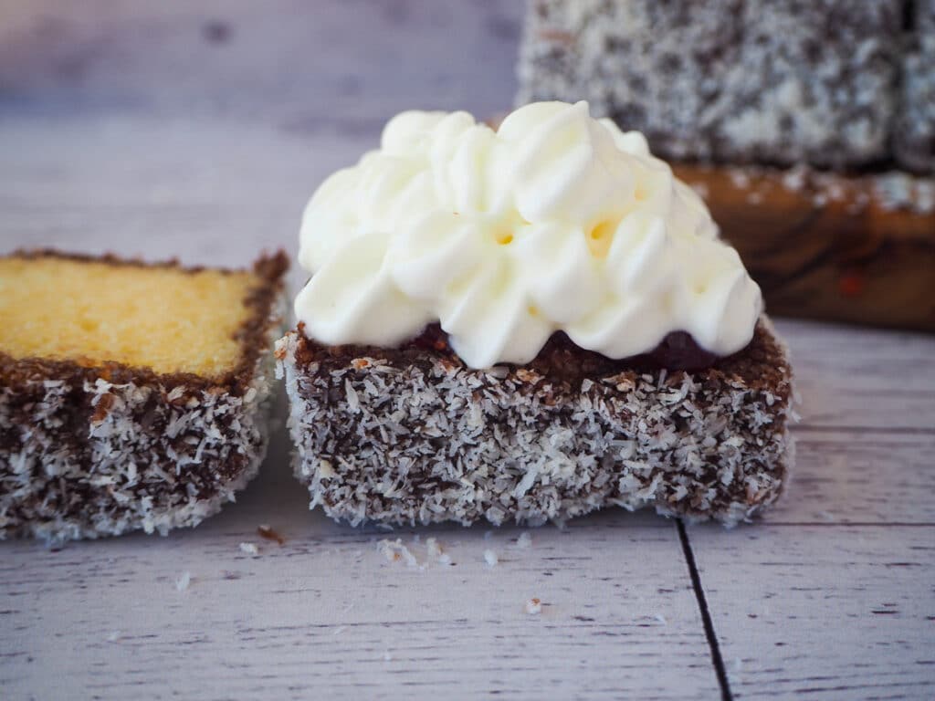 Lamington with jam and cream and lid still open.