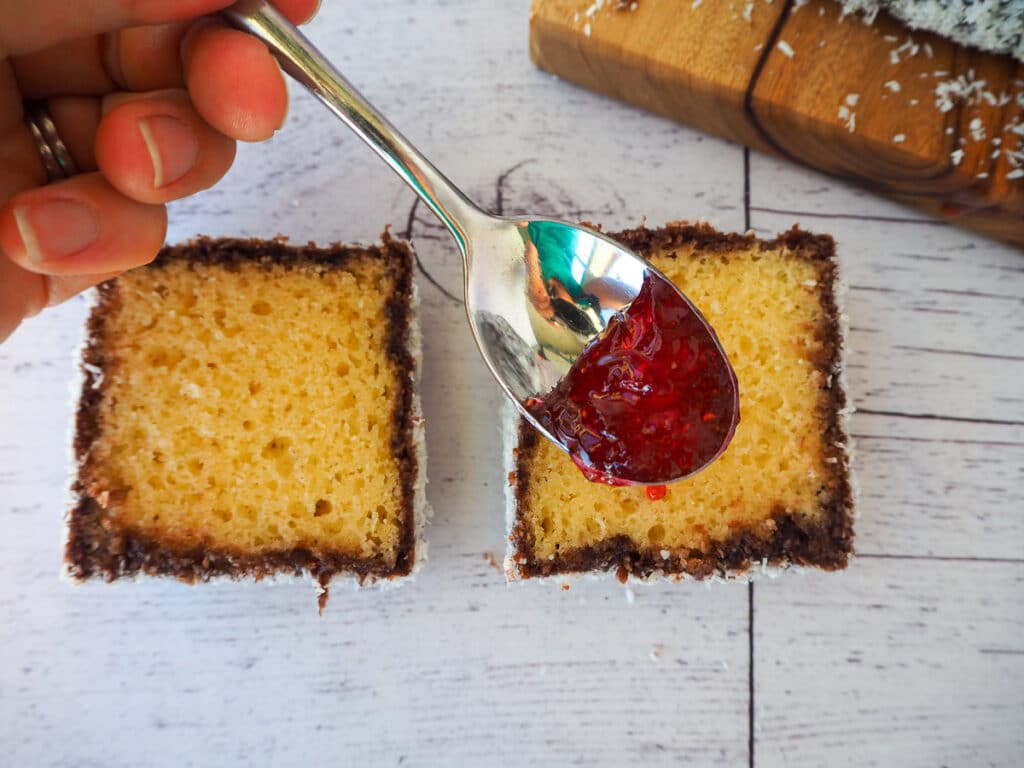 Spooning jam onto cut open lamington