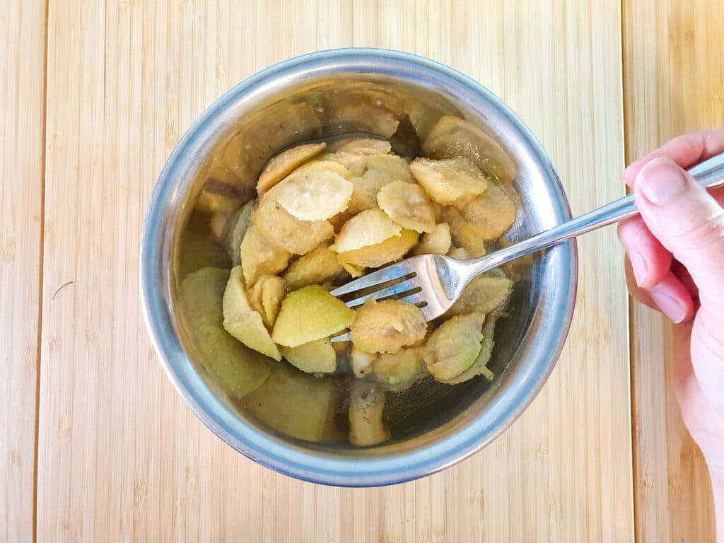 Lightly mashing feijoa flesh with a fork.