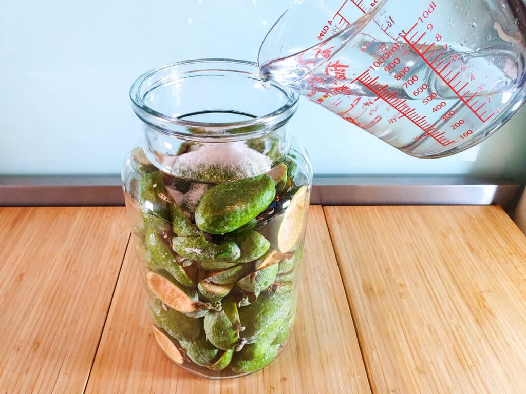 Adding water to jar with feijoa skins.