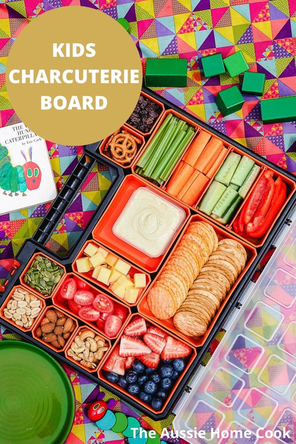 Charcuterie board on a picnic blanket with kids toys.